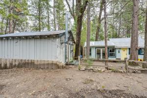 a small white house with a fence and trees at Serene Bass Lake Cabin Near Shopping and Dining! in Bass Lake