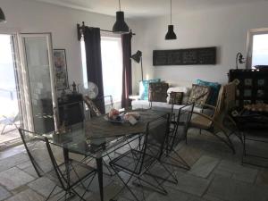 Villa Paloma, Tinos Island في Kardhianí: غرفة معيشة مع طاولة وكراسي زجاجية