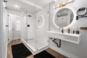 a white bathroom with a shower and a mirror at Mendo Bungalow in Mendocino