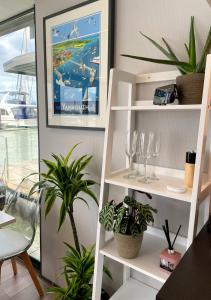 a room with white shelves with glasses and plants at Yarmouth Waterlodge Floating Apartment 1 in Yarmouth