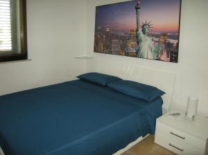 レウカにあるAttico del sole e del mareの青いベッドと自由の像が備わるベッドルーム1室