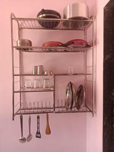 a metal shelf with dishes and utensils on it at KIYAN VILLA in Daman