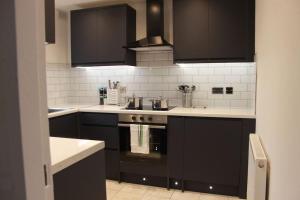 a kitchen with black cabinets and a stove at Stunning 3 bedrooms Entire flat in Harlow, Essex in Harlow