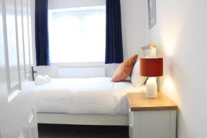 um quarto com uma cama branca e uma janela em Stunning 3 bedrooms flat at Orchard House em Harlow