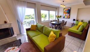 a living room with a green couch and a table at Dea Del Mare complex in front of the sea. in Sounio