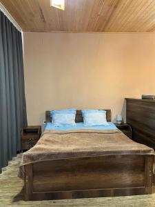a bedroom with a large bed with blue pillows at Lela Guest House in Mestia