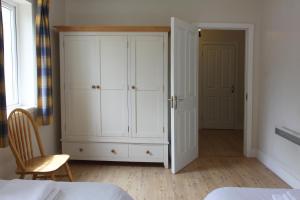 1 dormitorio con armario blanco y cama en Leitrim Quay - Riverside Cottage 3, en Leitrim