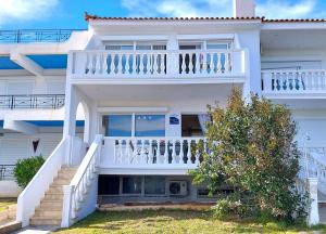 a white house with a balcony and stairs at Dea Del Mare complex in front of the sea. in Sounio