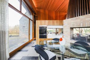 a dining room with a glass table and a kitchen at Villa Architecte des années 70 in Vif