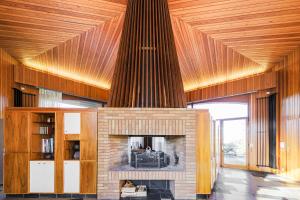 a fireplace in a living room with a wooden ceiling at Villa Architecte des années 70 in Vif