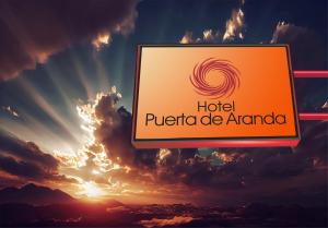 a sign for a hotel puerto encantado against a sunset at Hotel y Restaurante Puerta de Aranda in Aranda de Duero