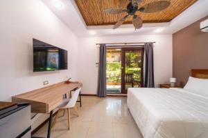 Schlafzimmer mit einem Bett, einem Schreibtisch und einem Deckenventilator in der Unterkunft Hotel Arco Iris in Tamarindo