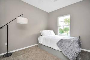 a white bedroom with a bed and a lamp at Rodeo Ready!!!! Modern 3 bedroom home in Houston