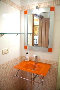 baño con lavabo de color naranja y espejo en Apartamentos Valdecarzana Senda del Oso, en San Martín