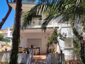 uma casa branca com uma mesa e uma palmeira em 4 bedrooms house at Punta Umbria 100 m away from the beach with terrace and wifi em Punta Umbría