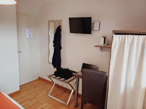 ドゥアルヌネにあるLes Terrasses du Risのデスク、椅子、テレビが備わる客室です。