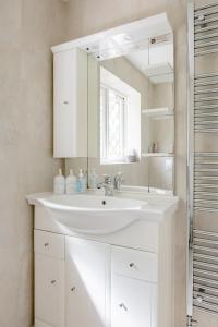 a white bathroom with a sink and a mirror at Ross House in Black Notley