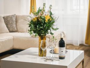 una botella de vino y un jarrón con flores en una mesa en Apartmán Měšťanský dům, en Jindřichův Hradec