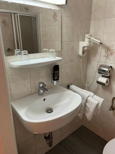 a bathroom with a white sink and a mirror at Hotel Post 22 in Braunau am Inn +14 photos
