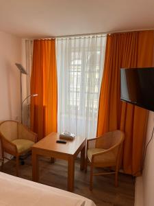 um quarto com uma mesa, uma televisão e uma cama em City Hotel Post 22 em Braunau am Inn