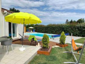 patio z żółtym parasolem i basenem w obiekcie Villa de 2 chambres avec piscine privee terrasse et wifi a Saint Gaudens w mieście Saint-Gaudens