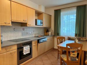 a kitchen with wooden cabinets and a table with a dining room at Appartements Sonnwend in Gerlos