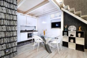 cocina y comedor con mesa de cristal y armarios blancos en Stesicoro Exclusive House, en Catania