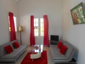 a living room with two gray couches and red pillows at Ô PARADIS TERRESTRE in Capesterre-de-Marie-Galante