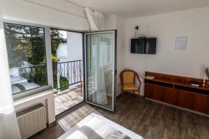 a room with a balcony with a desk and a window at Haus Koinonia 