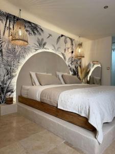 um quarto com uma grande cama branca com plantas na parede em LoveRoom, La suite de l’extase em Puget-sur Argens