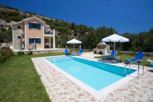 a pool with chairs and umbrellas next to a house at Regina Ioanna Villas in Ayia Evfimia