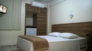 1 dormitorio con 1 cama y TV en Bevile Hotel, en Cataguases
