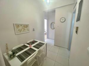 a white room with a table and a clock on the wall at AKTIS apartment 3 near airport in Artemida