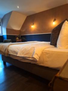 um quarto com uma cama grande com lençóis brancos e almofadas em Chambres d'hôtes - Au Clos d'Amande em Lasne