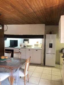 a kitchen with a table and a white refrigerator at Le pigeonnier maison de caractère logement 4 personnes La maisonnette rénovée logement 2 personnes in Floirac