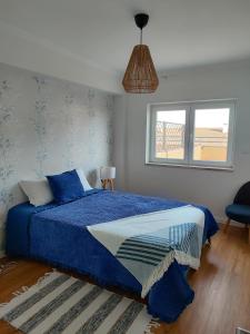 a bedroom with a bed with blue sheets and a window at zélu apartamento centro da Guarda in Guarda