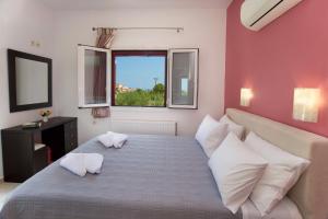 sypialnia z łóżkiem z białymi poduszkami i oknem w obiekcie Regina Ioanna Villas w mieście Agia Efimia