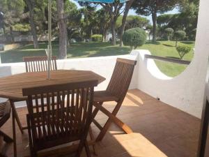 una mesa de madera con 2 sillas y una sombrilla en el patio en One bedroom appartement with shared pool terrace and wifi at Albufeira 4 km away from the beach en Albufeira