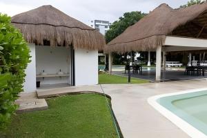 un resort con piscina e un edificio con tetto di paglia di Exclusive building 6 people 3 cable televisions 3 swimming pools balcony, a Cancún