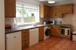 cocina con armarios de madera, lavadora y secadora en Leitrim Quay - Riverside Cottage 6, en Leitrim