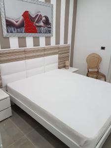 uma cama branca num quarto com uma fotografia na parede em La Vela Apulia Seaside Residence em Margherita di Savoia