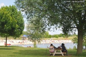 2 personnes assises sur une table de pique-nique près d'une plage dans l'établissement Chalet charmant à Clermont-Créans avec piscine partagée, à La Flèche