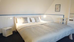 una camera da letto con un grande letto con lenzuola e cuscini bianchi di Marthas Insel a Oldenswort