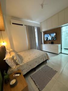 1 dormitorio con 1 cama y TV. en Acolhedor apartamento na quadra da praia, en Río de Janeiro