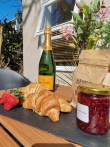 a table with a bottle of wine and a croissant and a strawberry at Seashells at 2 TRENCROM COURT ST IVES in Carbis Bay