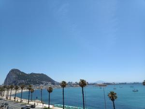 vistas a una playa con palmeras y al océano en Vistas a 3 Países y 2 Continentes 1º linea de Playa a 5 minutos de Gibraltar en La Línea de la Concepción