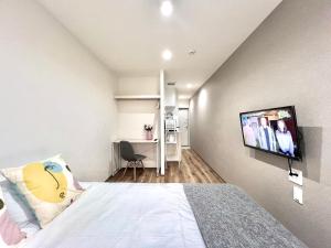 a bedroom with a bed with a flat screen tv on the wall at ANX Hostel in Tokyo