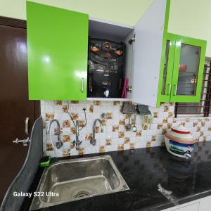 una cocina con fregadero y armarios verdes en Om Villa, en Bhopal