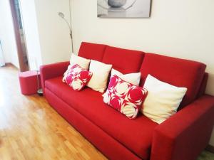 a red couch with four pillows on it at HIKARI, centro Luanco con PARKING in Luanco