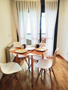 a dining room table with white chairs and a wooden table at HIKARI, centro Luanco con PARKING in Luanco